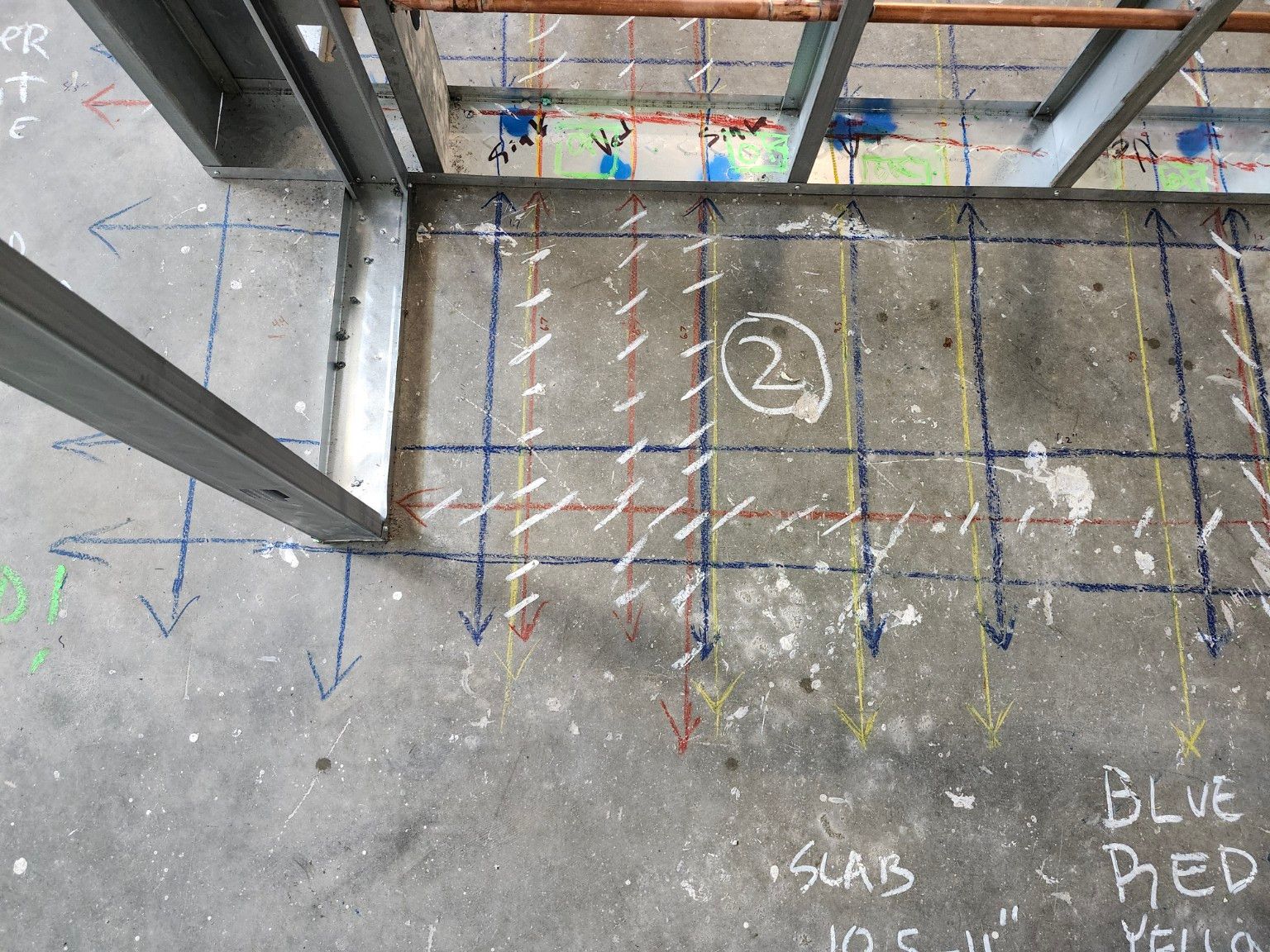 A floor slab beside a steel-stud wall with copper pipes, marked with parallel blue, red, and yellow lines running to the wall track, white hatching, and a circled area number.